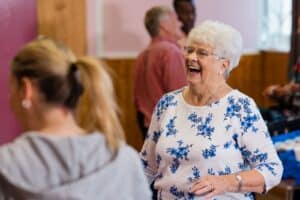 Elderly women laughs with high school friends at class reunion